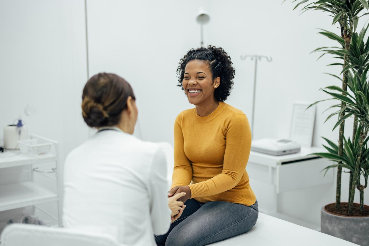 Physician holding hands with smiling patient