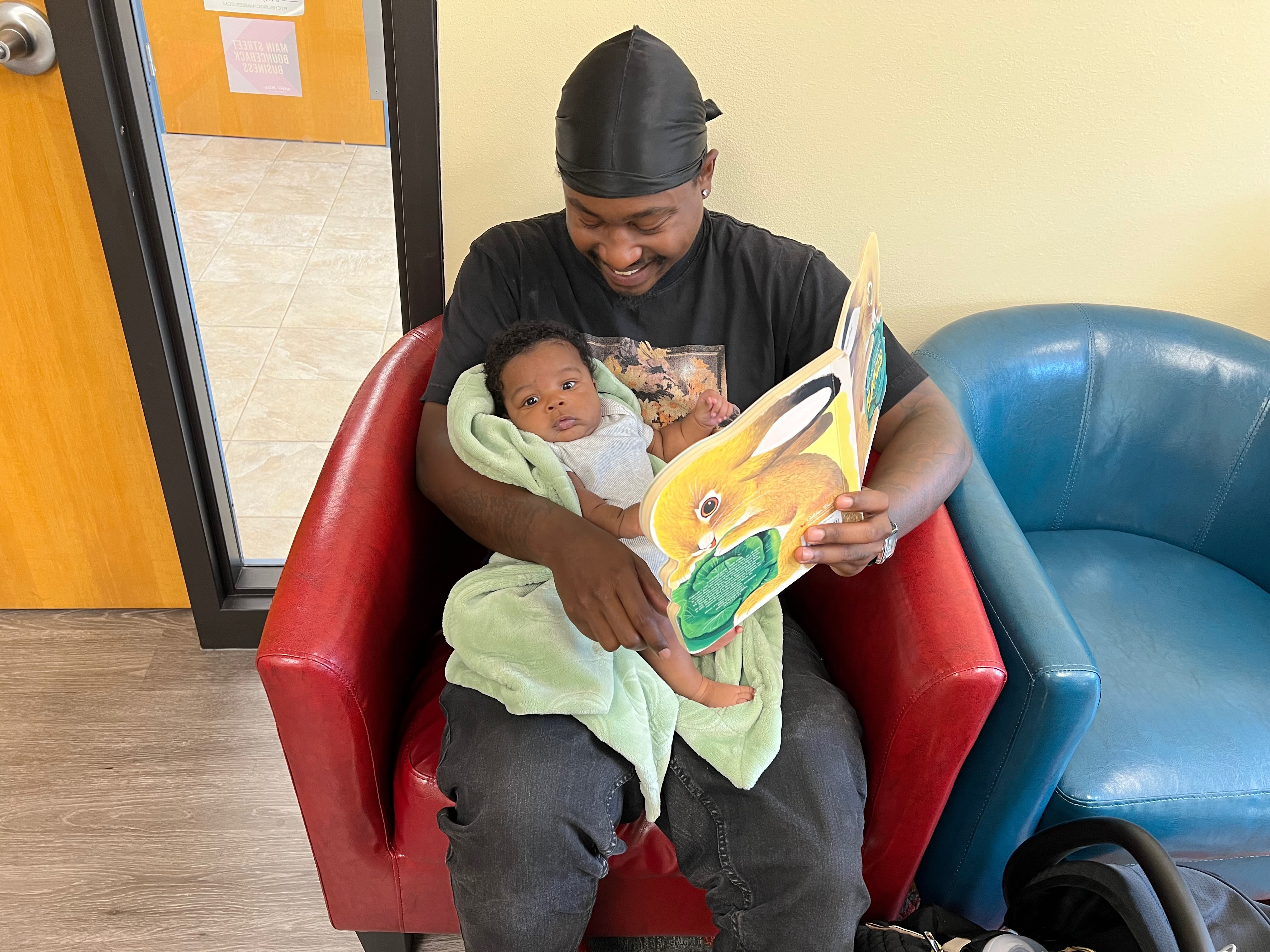 smiling parent holding baby and book