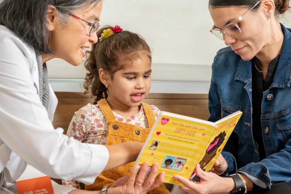 physician with parent and child holding a book